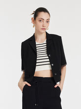 A lady wears a cropped black blazer.